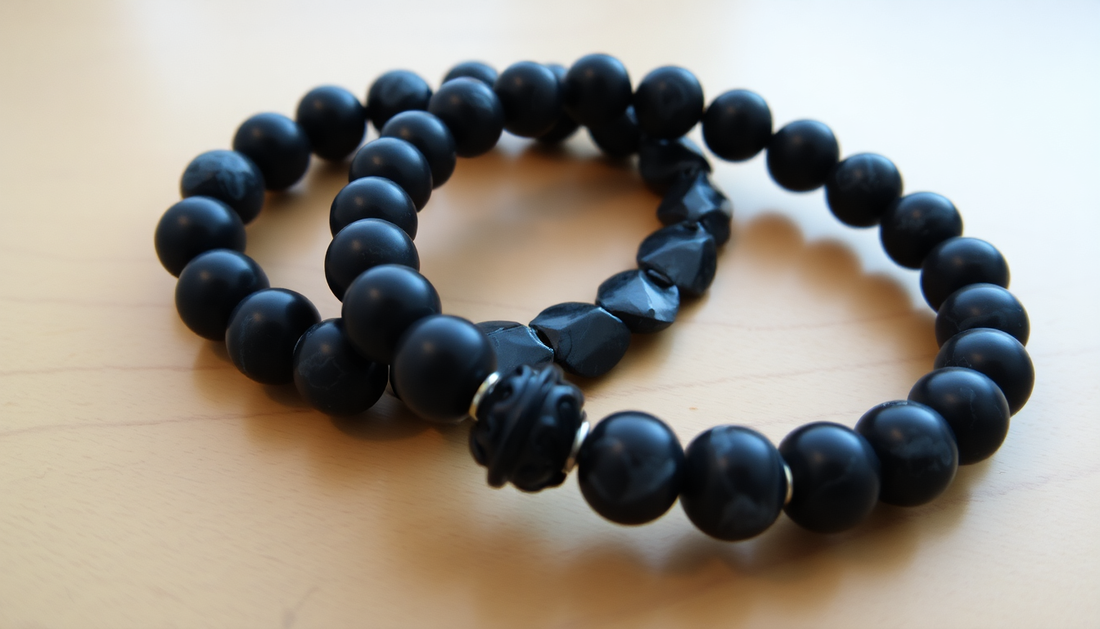 Two distinct black stone bracelets on a wooden table