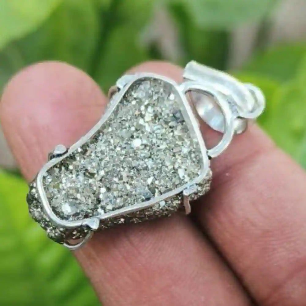 CRYSTCOP golden pyrite pendant with natural crystal texture set in silver frame on finger