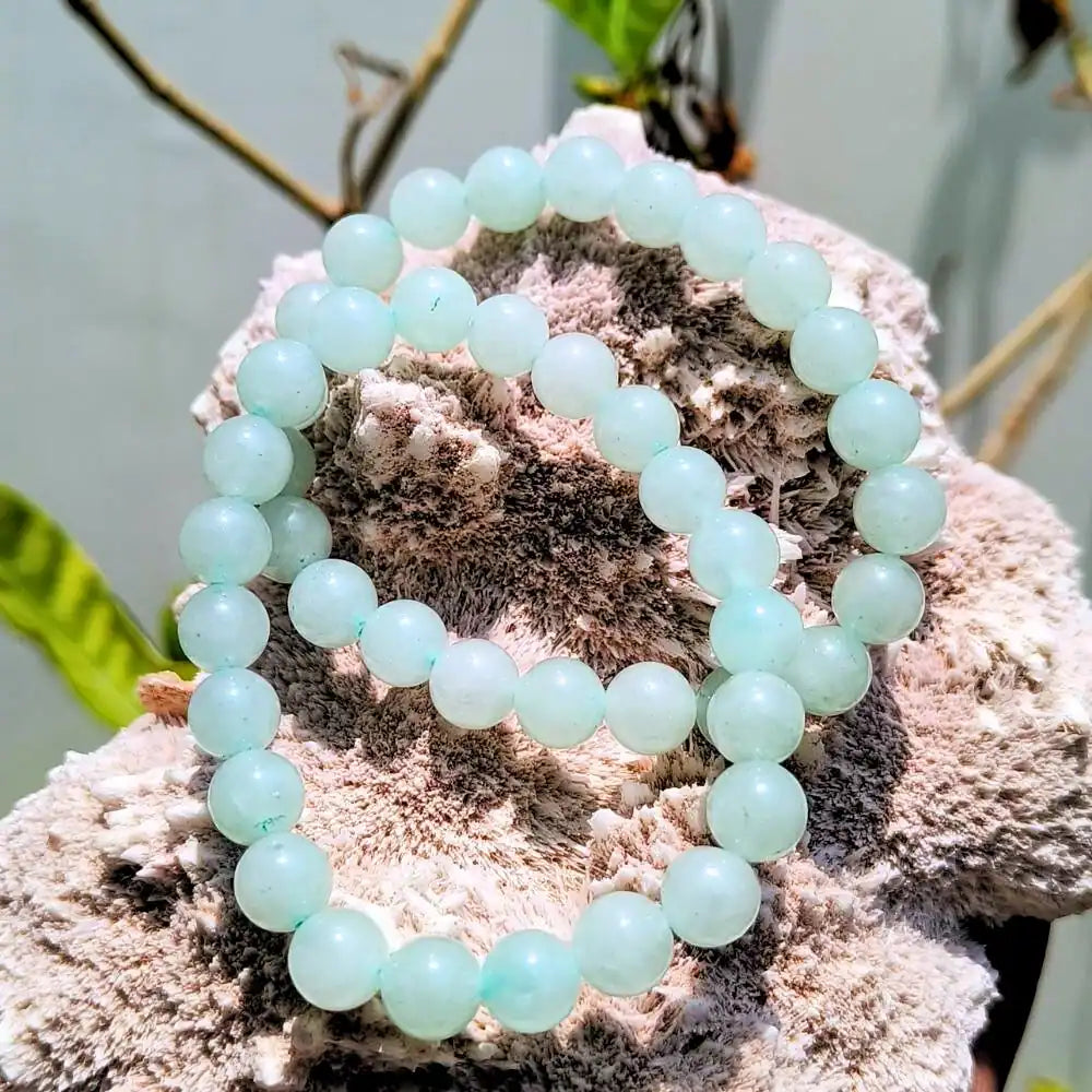 CRYSTCOP Green Aventurine Bracelet made of round polished beads displayed on a natural stone background
