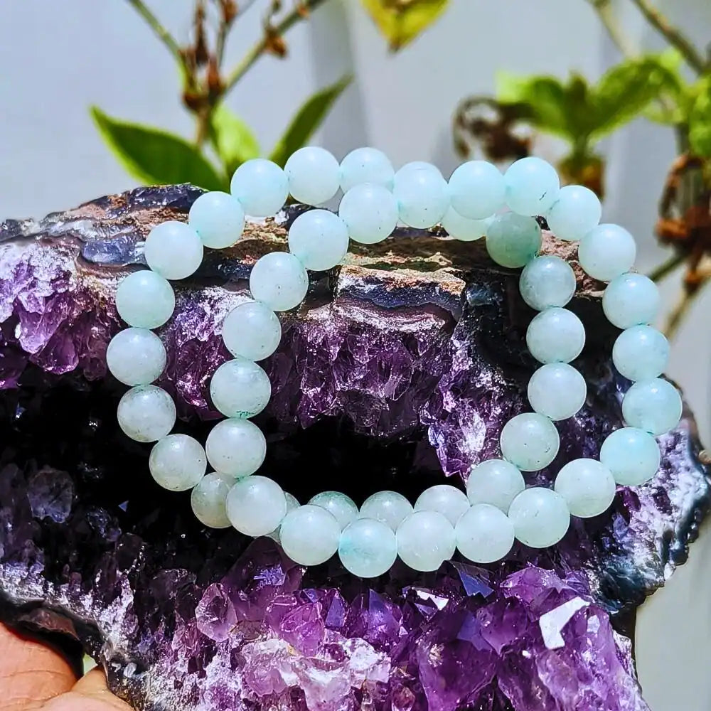CRYSTCOP Green Aventurine Bracelet with round beads displayed on purple amethyst crystal