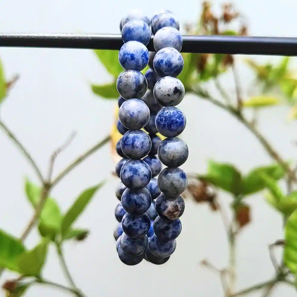 CRYSTCOP natural sodalite beaded bracelet with polished blue and gray stone beads hanging on a black rod