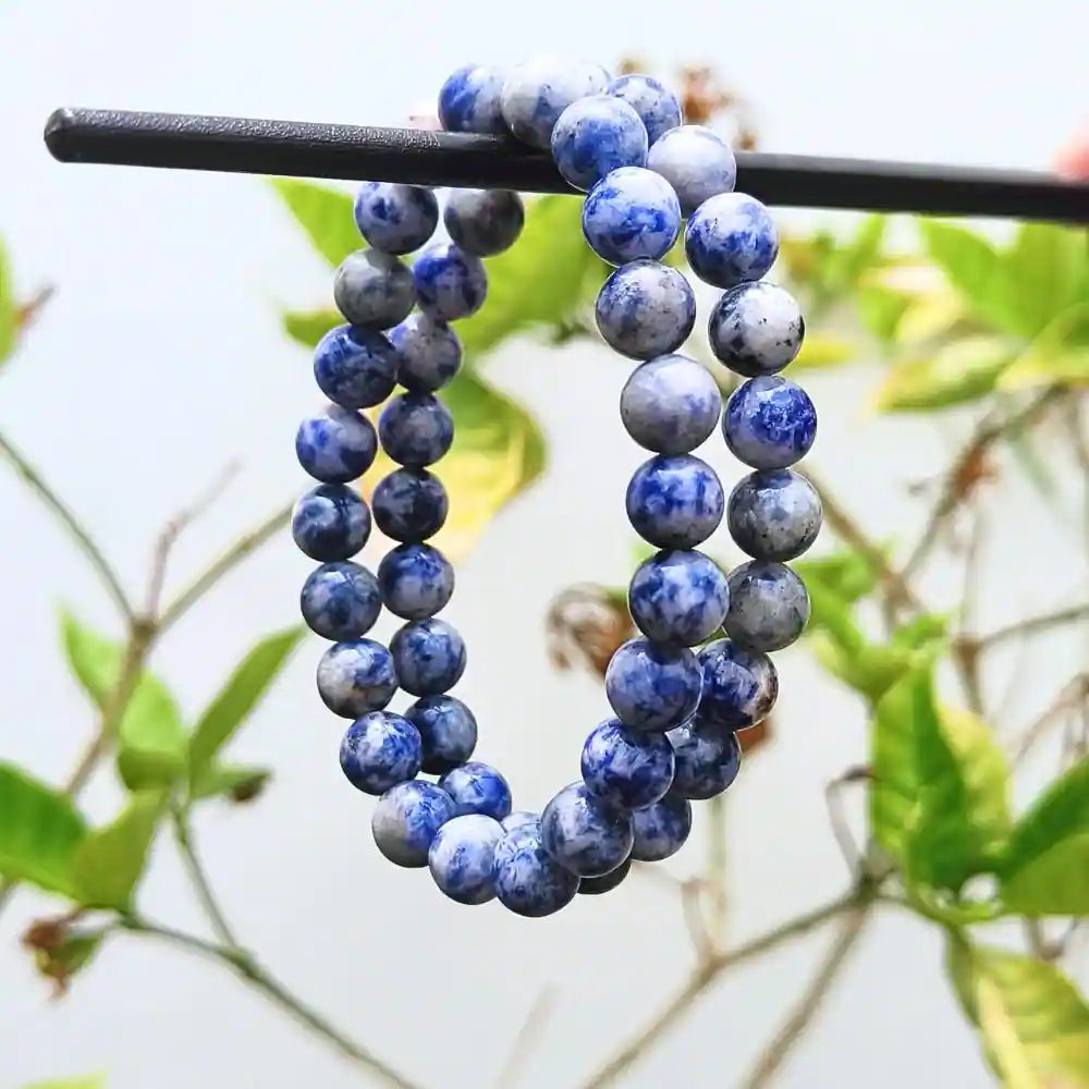 Natural sodalite beaded bracelet with blue and white marbled round stones hanging on a black rod