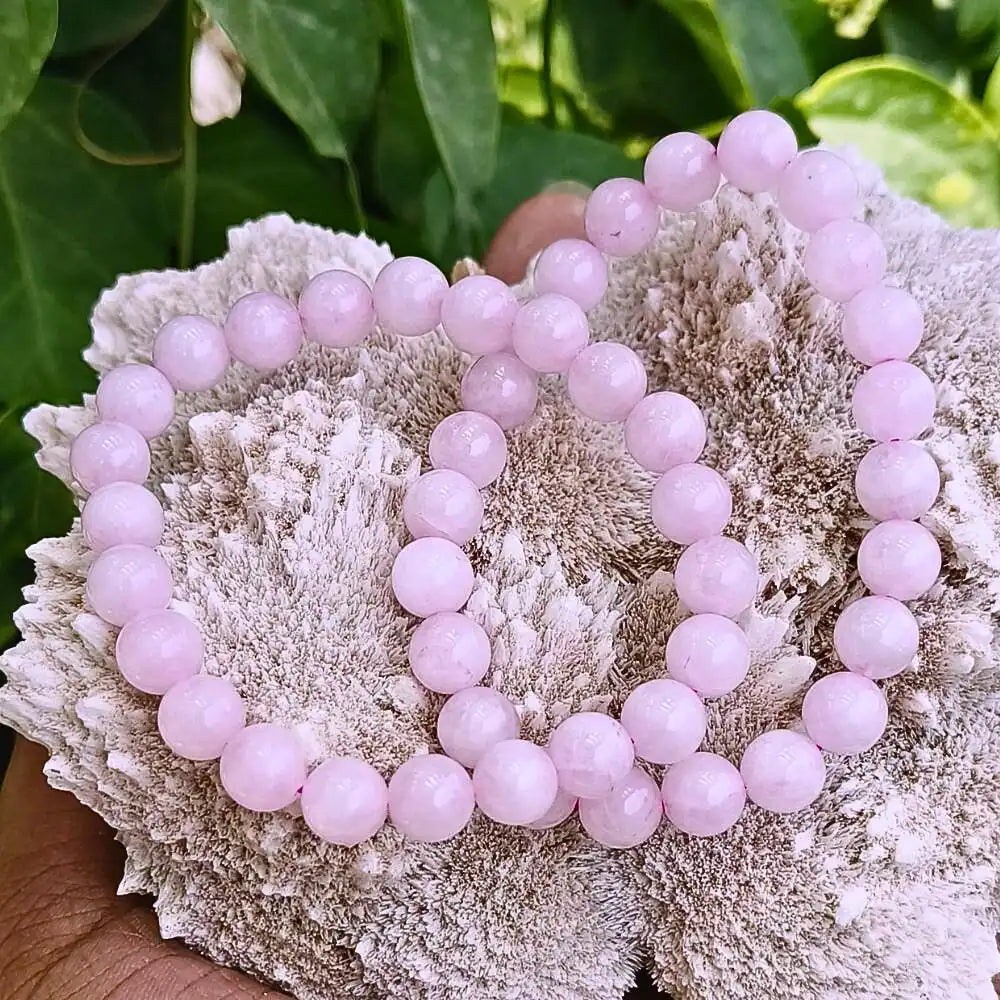 CRYSTCOP pink rose quartz energy jewelry beaded bracelets displayed on rough textured white coral