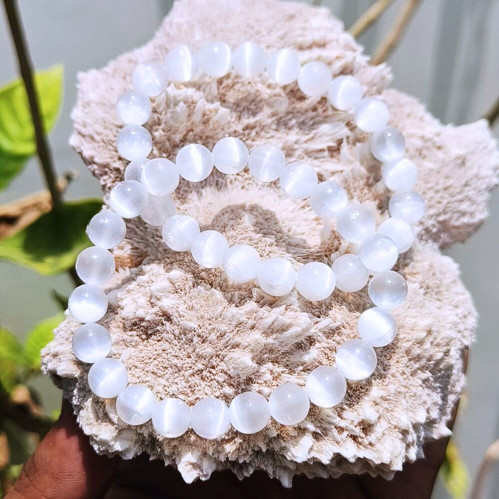 CRYSTCOP white selenite bracelet 8mm round beads displayed on a textured natural stone