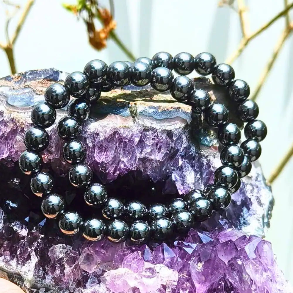 CRYSTCOP hematite bracelet 8mm with polished round beads displayed on a purple crystal stone