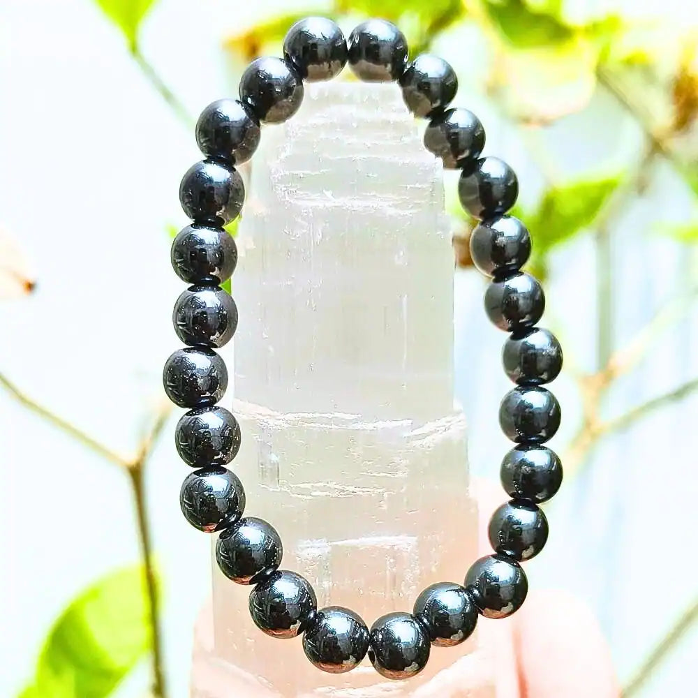 CRYSTCOP hematite bracelet 8mm with polished round beads displayed on a crystal stand