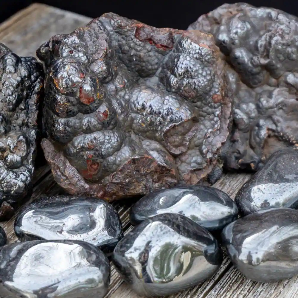 Collection of polished and rough hematite stones for healing displayed on a wooden surface