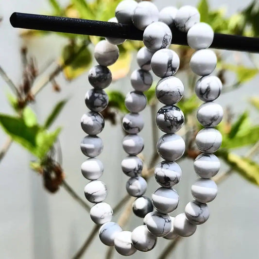 CRYSTCOP Howlite bracelet 8mm with white and gray marbled beads hanging on a black rod