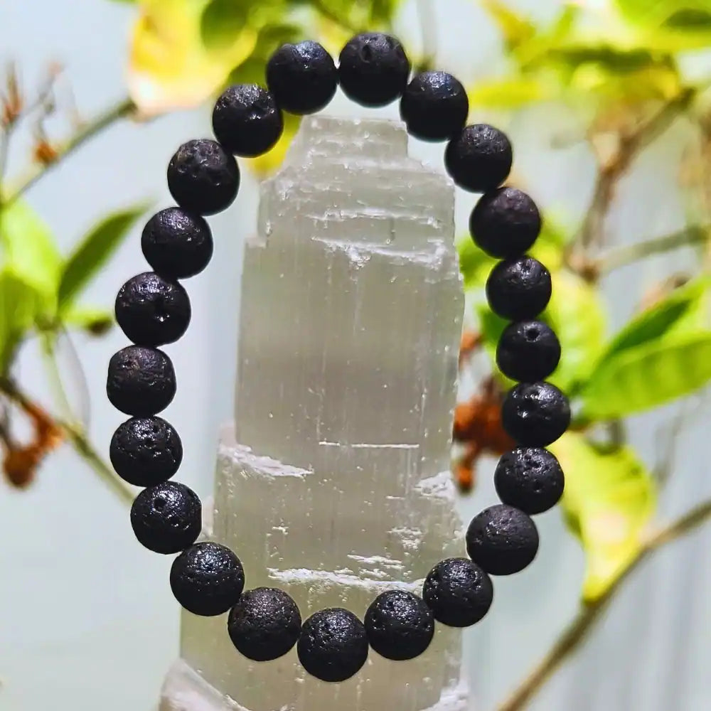 CRYSTCOP black lava bracelet with textured round beads displayed on a crystal stand