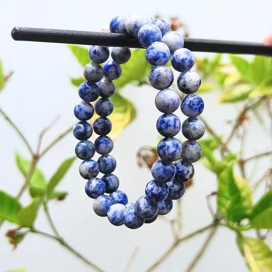 Natural sodalite beaded bracelet with blue and white marbled round stones hanging on a black rod