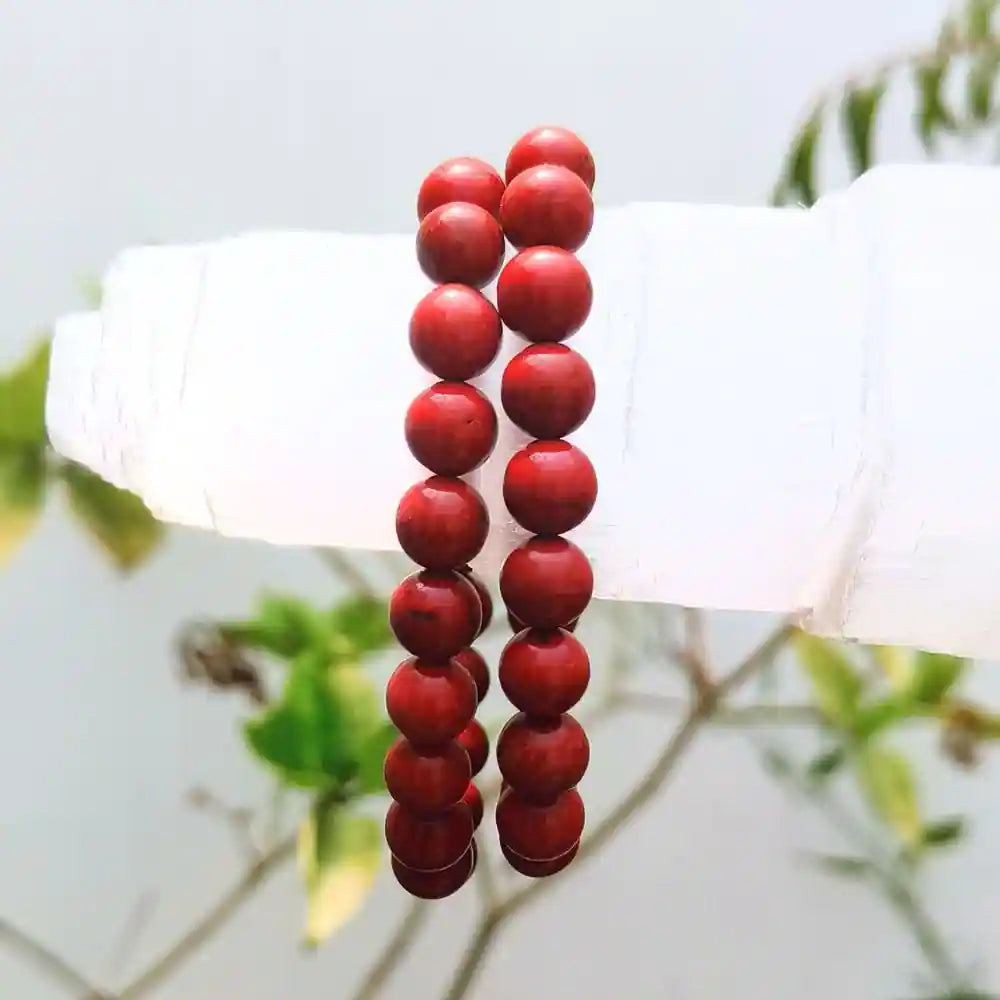 CRYSTCOP red jasper bracelet with smooth round beads displayed on a white stand