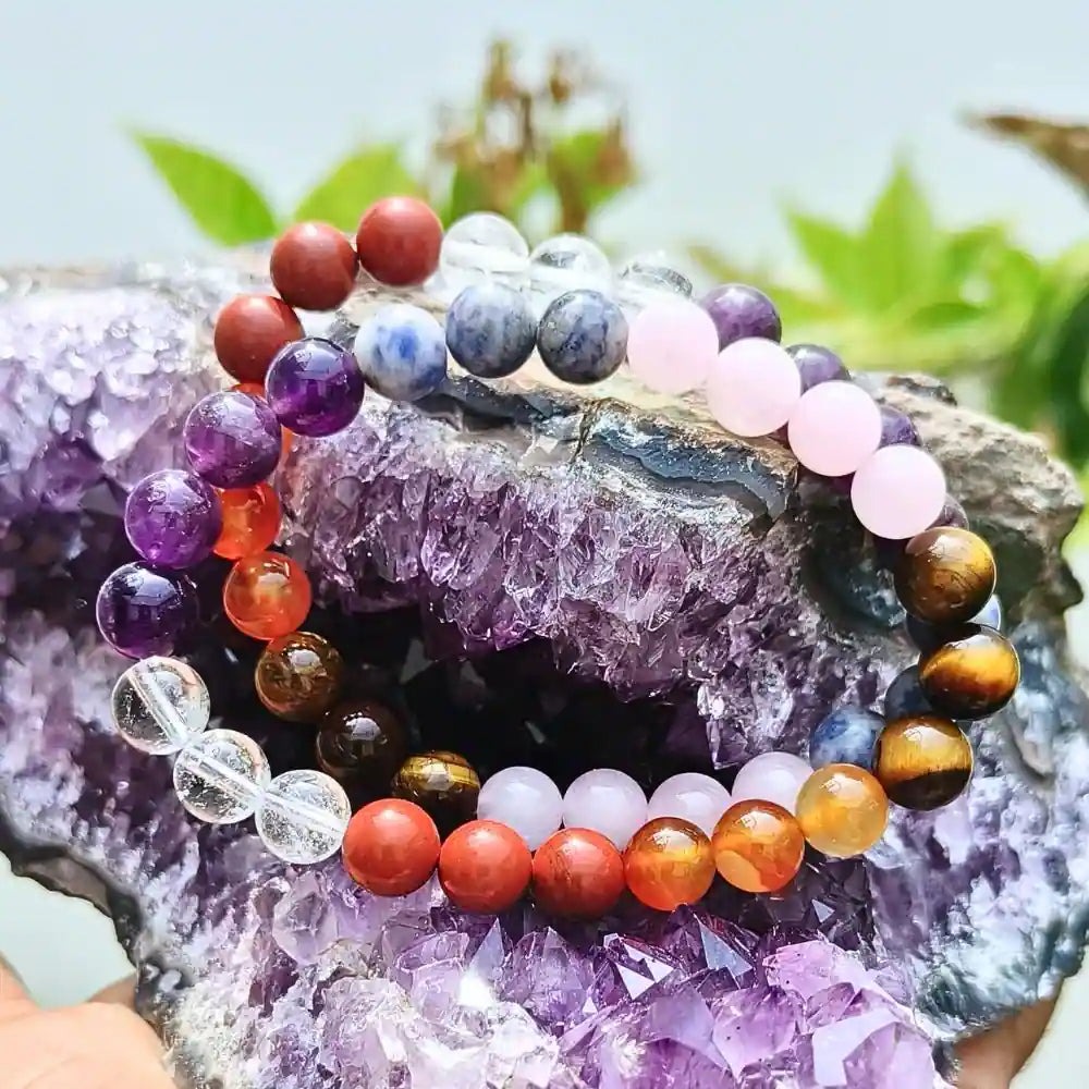 CRYSTCOP gemstone chakra bracelet with multicolored natural stones displayed on a purple crystal geode
